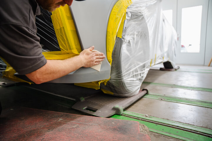 AutoLux technician wiping down bodywork on a prepared car.